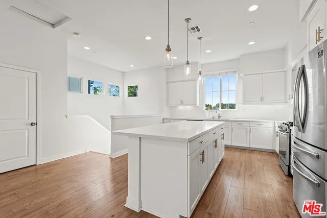 a large kitchen with a large counter top a sink stainless steel appliances and cabinets