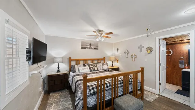 a bedroom with furniture a flat screen tv and a window