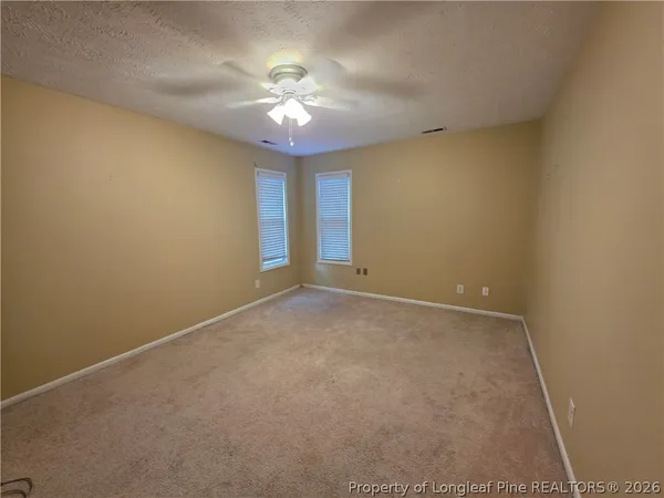 en empty room with windows and chandelier fan