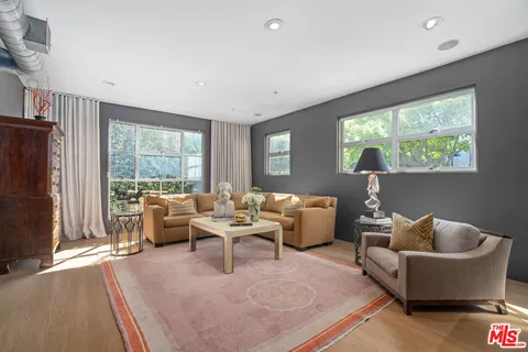 a living room with stainless steel appliances furniture a rug and a view of kitchen
