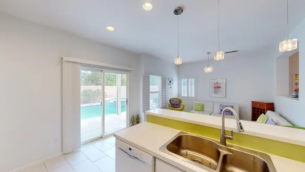 a kitchen with a sink a counter top space and living room view