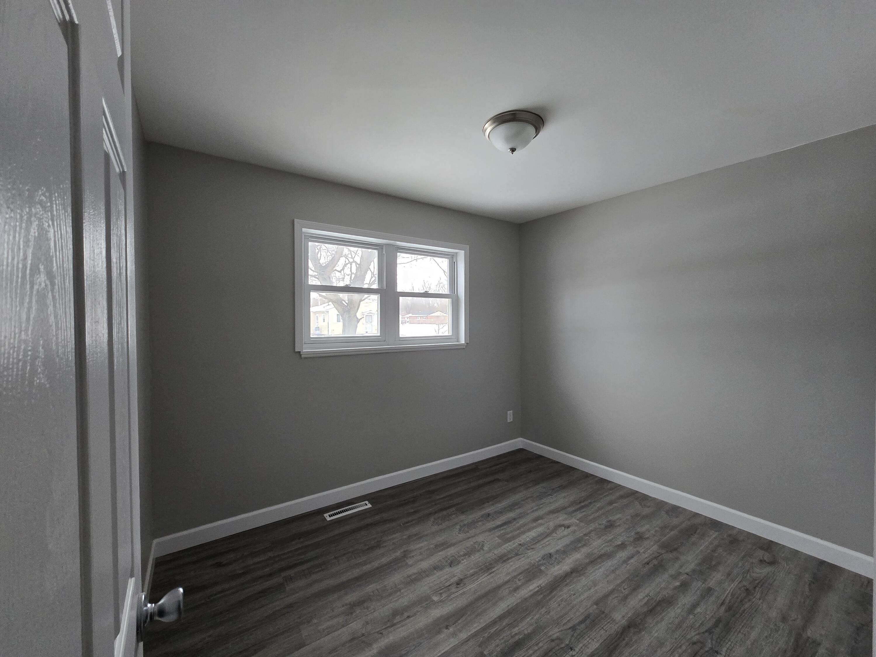 1044 Hobart Street Gary, IN 46406 - Photo 12 of 22 an empty room with wooden floor and windows
