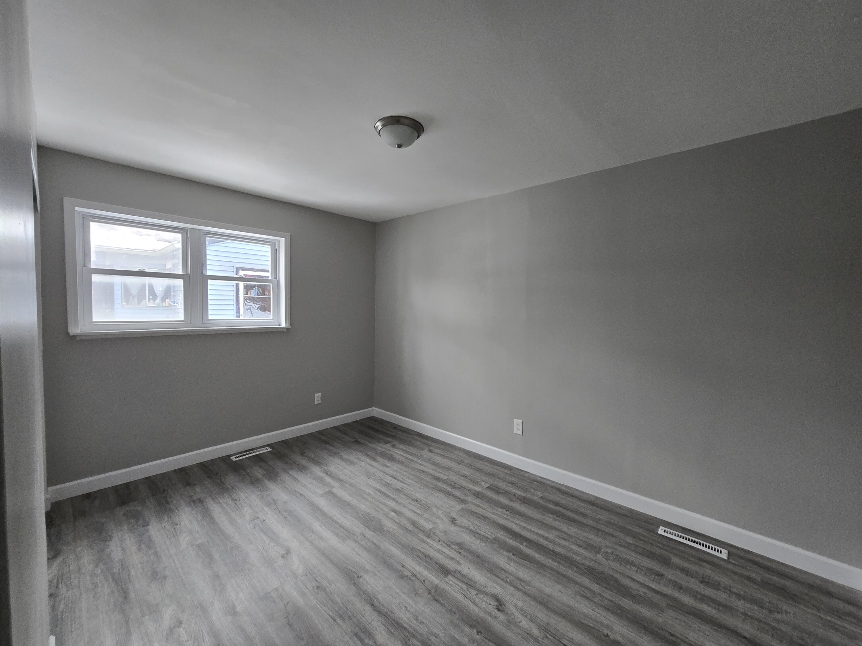 1044 Hobart Street Gary, IN 46406 - Photo 18 of 22 a view of an empty room with wooden floor and a window