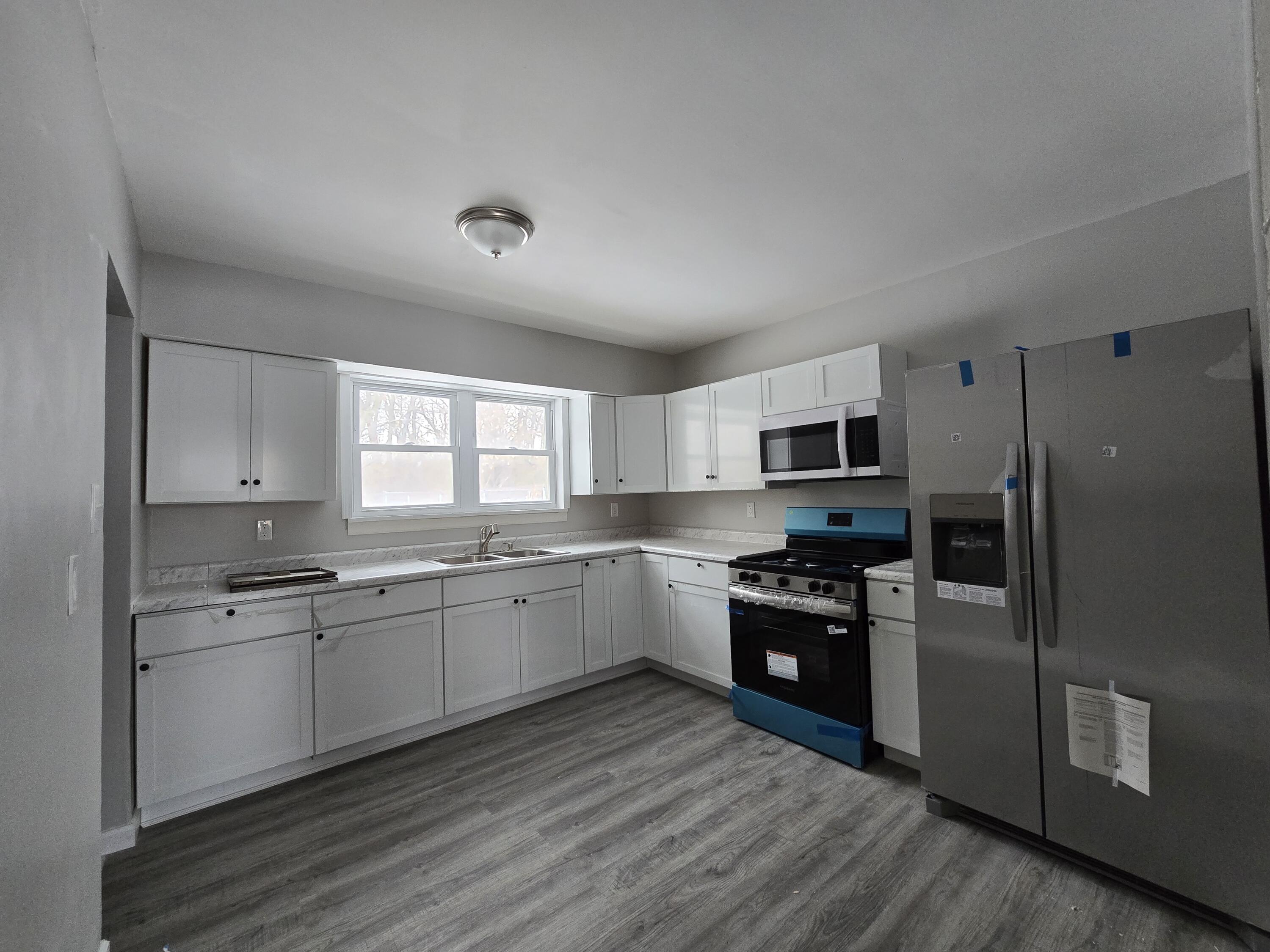 1044 Hobart Street Gary, IN 46406 - Photo 7 of 22 a kitchen with stainless steel appliances granite countertop a stove top oven a sink and dishwasher a refrigerator with wooden floor