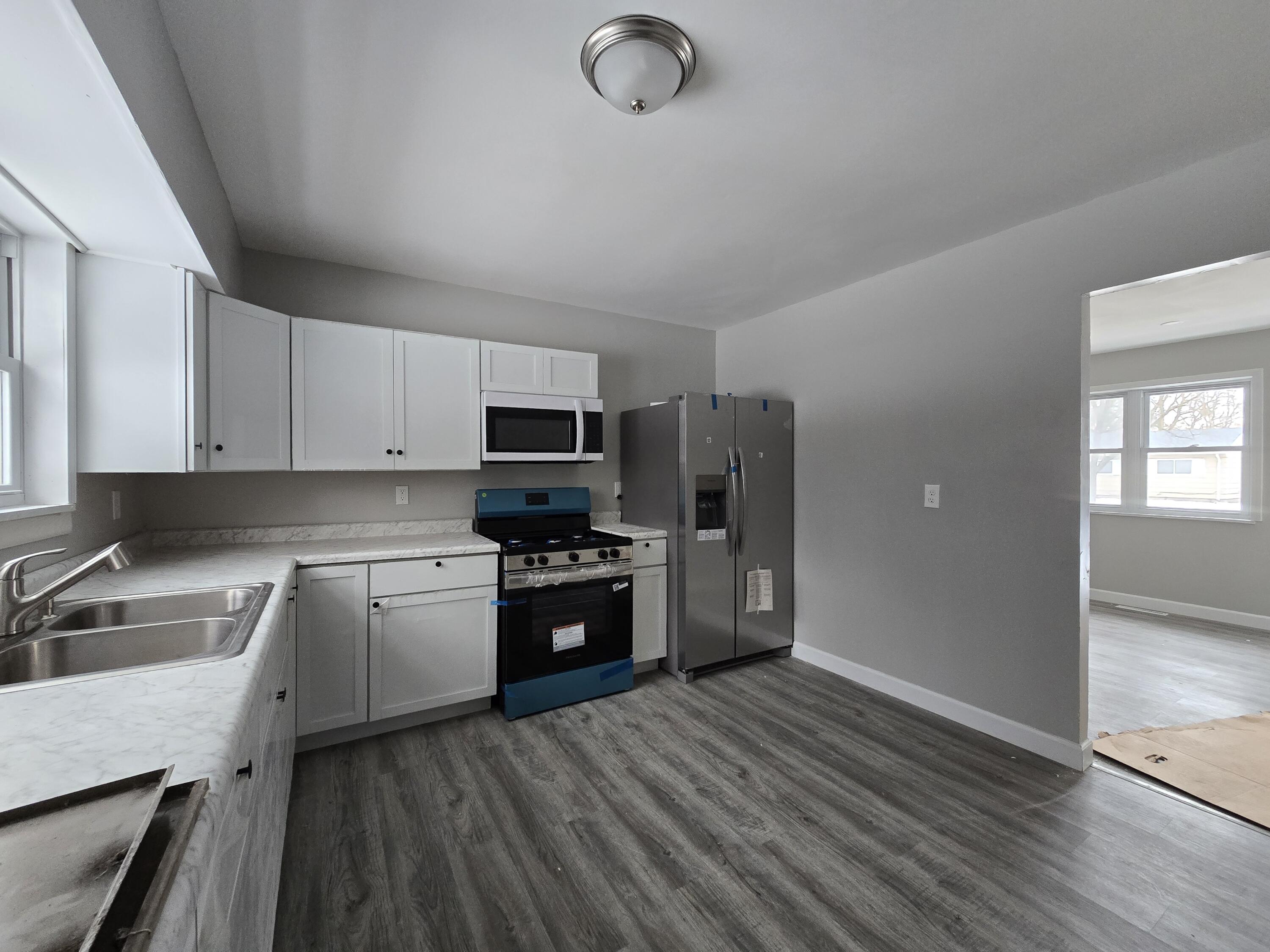 1044 Hobart Street Gary, IN 46406 - Photo 10 of 22 a kitchen with stainless steel appliances granite countertop a refrigerator a sink dishwasher a stove oven and white countertops with wooden floor