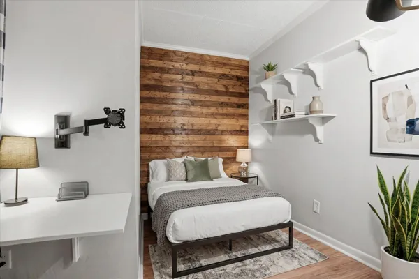 a bedroom with a bed and a potted plant on the dresser