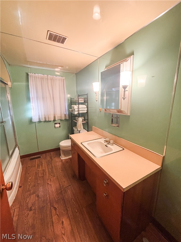 724 East Main Street Barnesville, OH 43713 - Photo 15 of 28 Bathroom with dark wood-type flooring, vanity, and bath / shower combo with glass door
