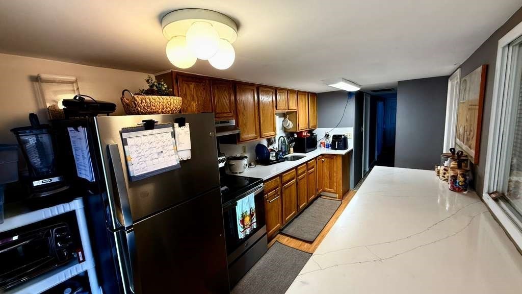 98 School Street Lowell, MA 01854 - Photo 23 of 40 a large kitchen with stainless steel appliances granite countertop a refrigerator and a stove top oven