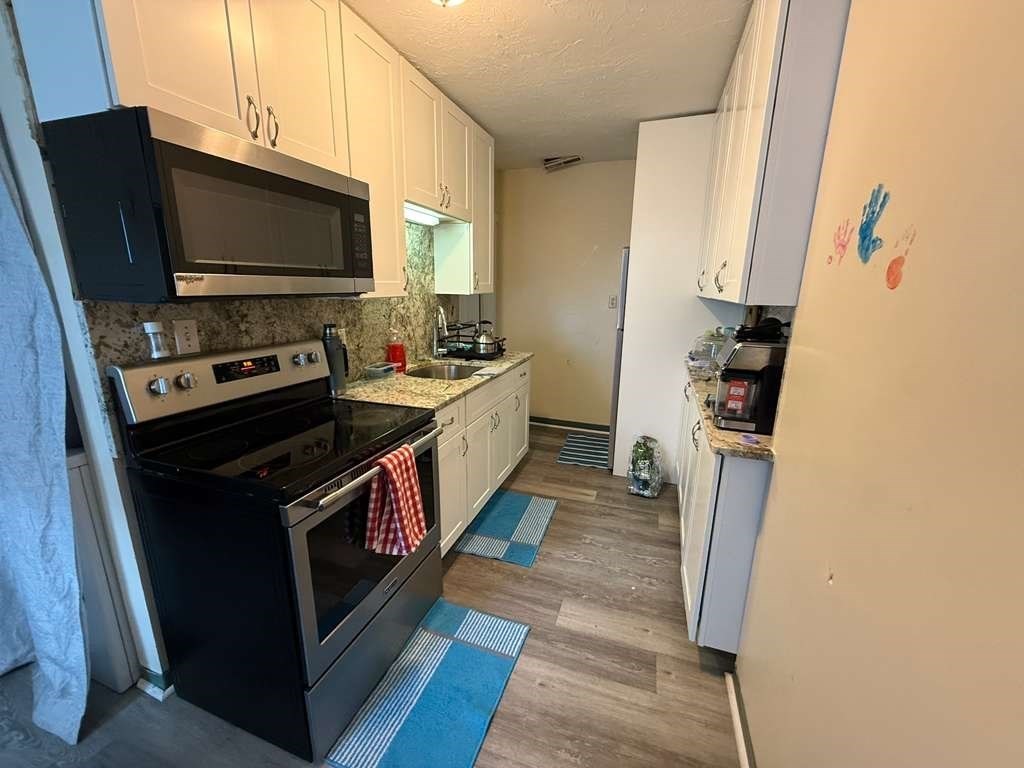 98 School Street Lowell, MA 01854 - Photo 7 of 40 a kitchen with a stove and a microwave