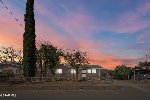 a front view of a house with a garden and trees