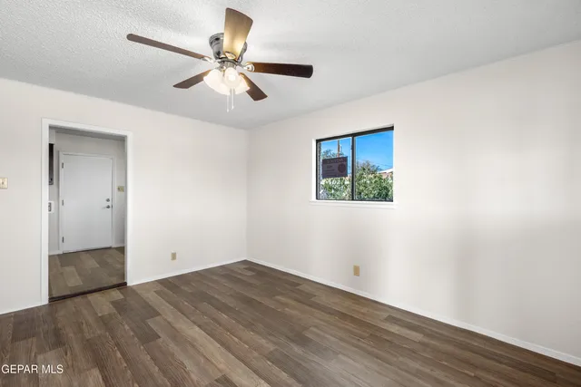 an empty room with wooden floor and ceiling fan