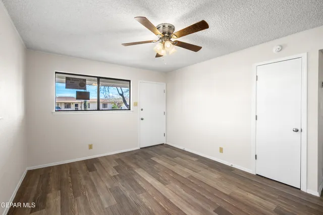 an empty room with wooden floor and ceiling fan