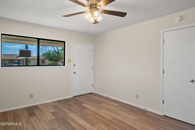 a view of empty room with wooden floor and fan