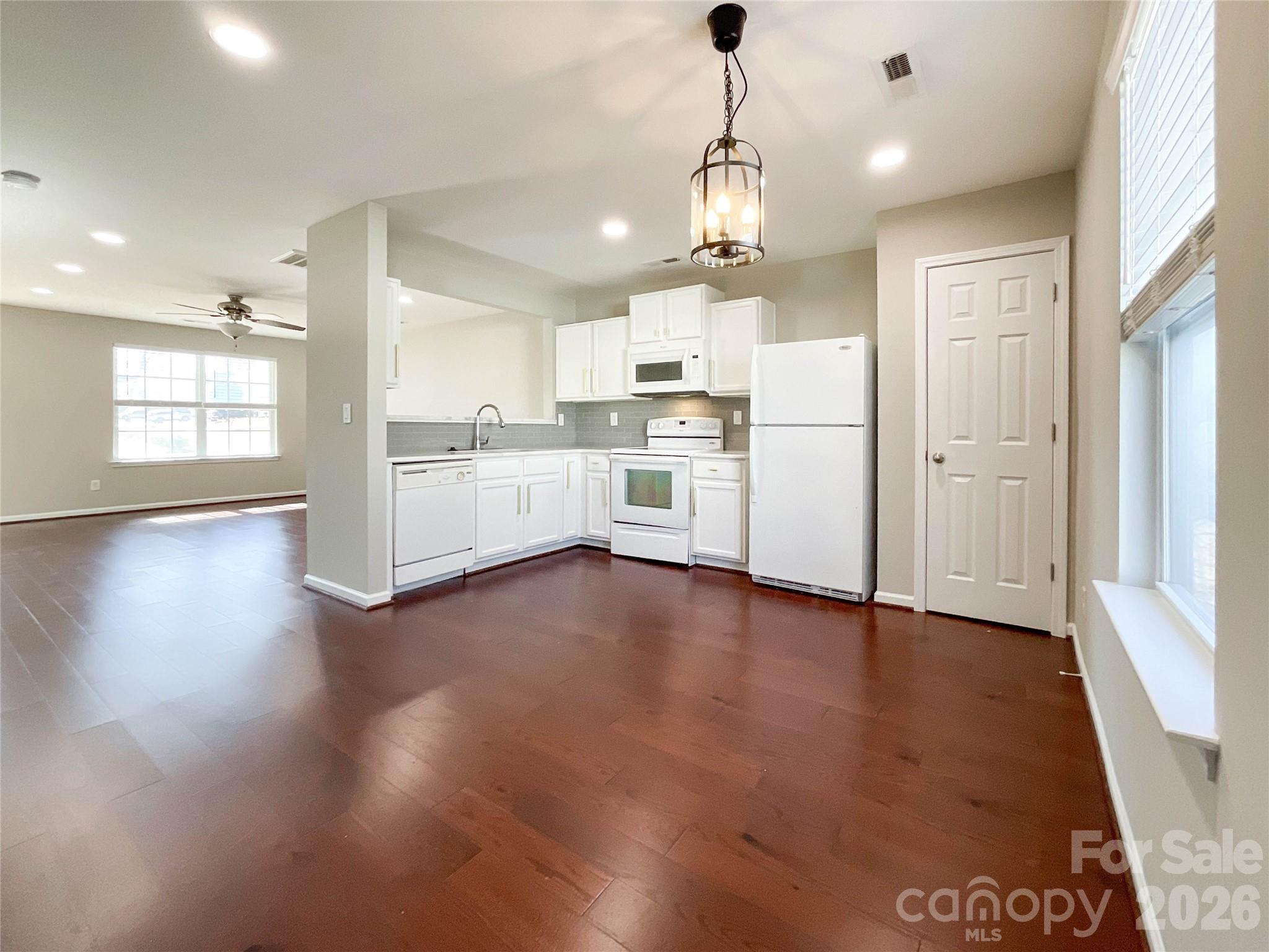 301 Foster Lane Albemarle, NC 28001 - Photo 15 of 41 an open kitchen with a refrigerator a sink dishwasher a stove and white cabinets with wooden floor