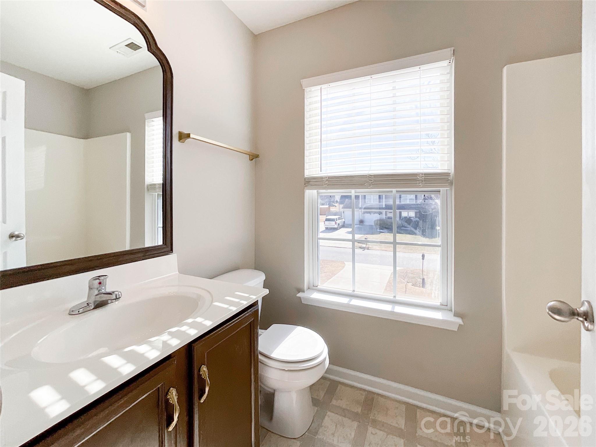 301 Foster Lane Albemarle, NC 28001 - Photo 33 of 41 a bathroom with a granite countertop sink toilet a large mirror and a window