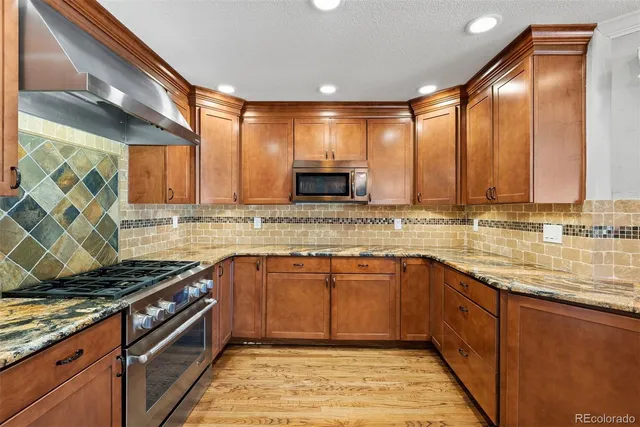 a kitchen with stainless steel appliances granite countertop a stove a sink and a microwave