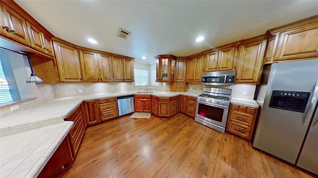 10702 Crosby Lynchburg Road Highlands, TX 77562 - Photo 14 of 18 a kitchen with stainless steel appliances a stove a sink a refrigerator white cabinets and wooden cabinets