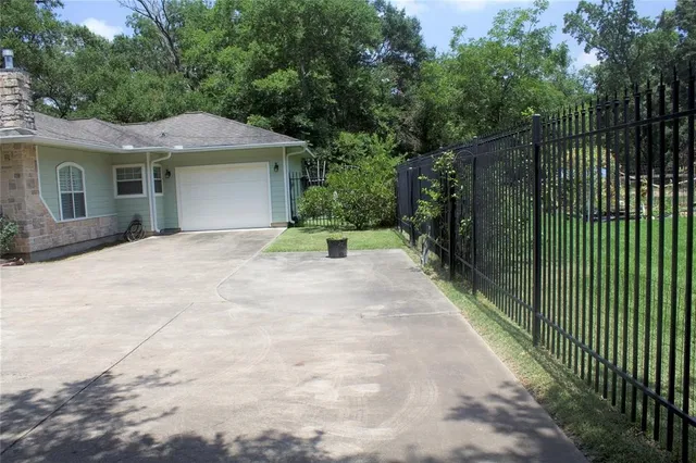 a view of a house with a small yard plants and a large tree