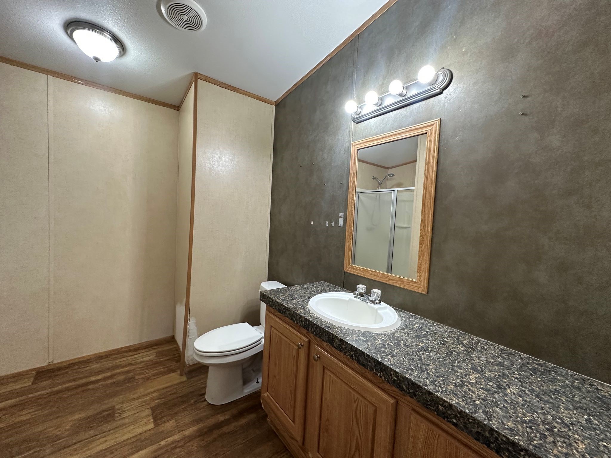 29 Brumley Street Huntsville, TX 77320 - Photo 13 of 17 a bathroom with a granite countertop sink toilet a mirror and a shower