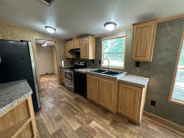 a kitchen with granite countertop a sink stove and refrigerator