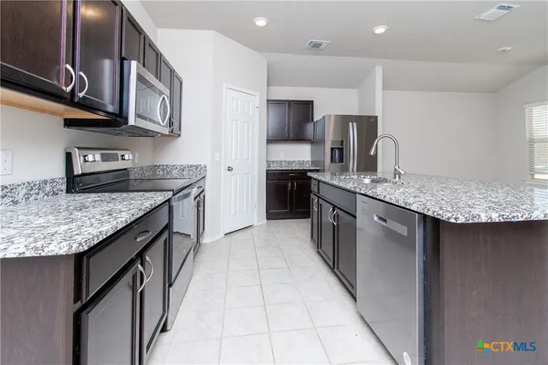 a kitchen with stainless steel appliances granite countertop a sink stove and refrigerator