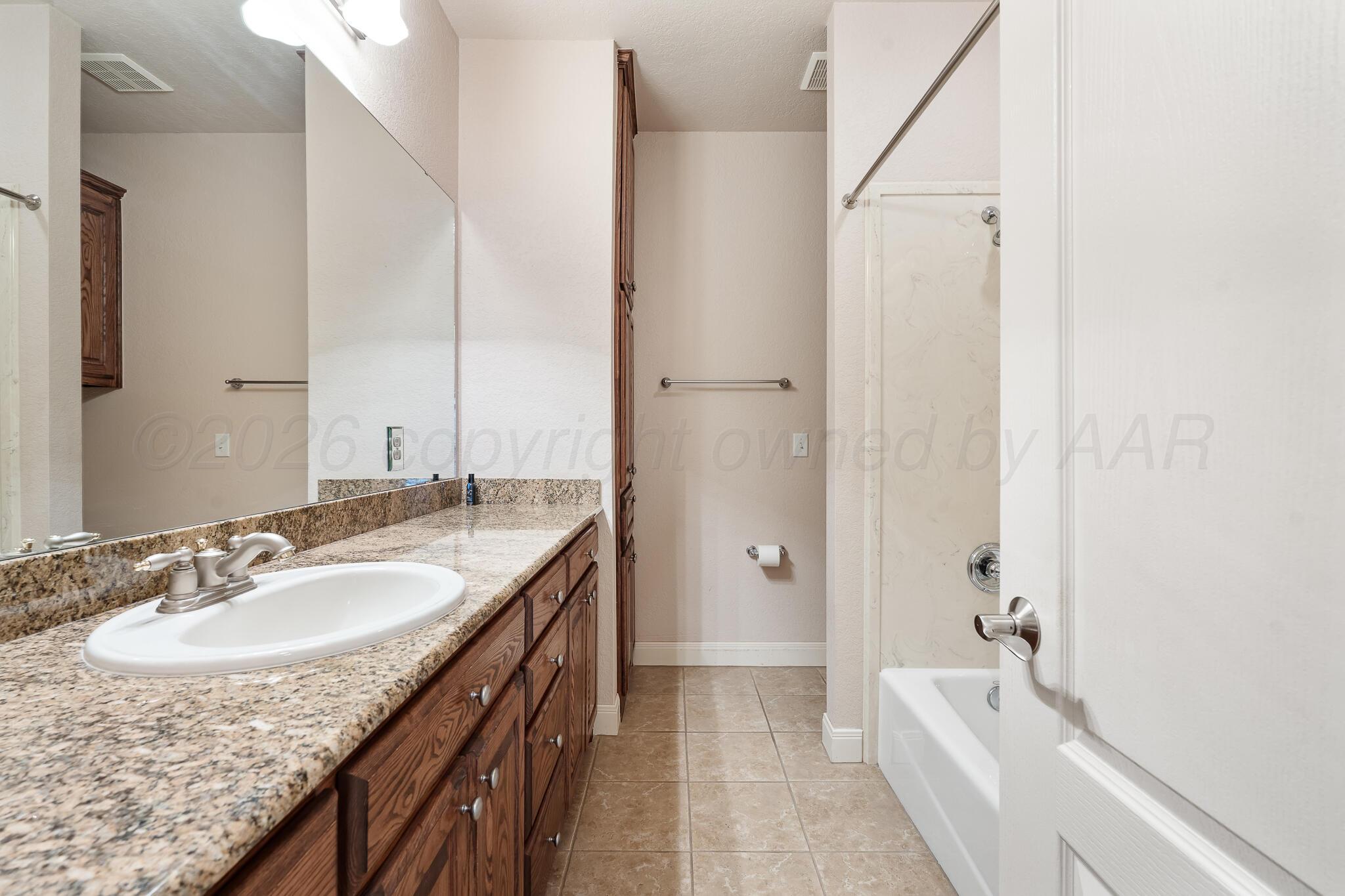 5008 Wesley Road Amarillo, TX 79119 - Photo 35 of 47 a bathroom with a granite countertop sink a mirror and a bathtub