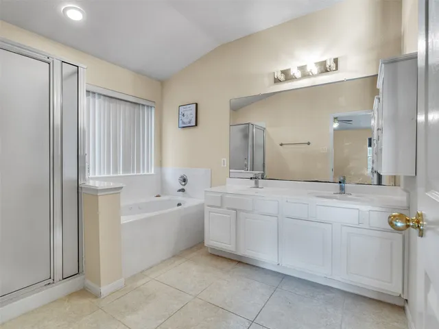 a spacious bathroom with a double vanity sink a mirror and a bathtub
