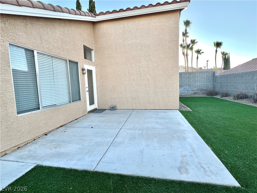 9708 Ridge Creek Place Las Vegas, NV 89134 - Photo 39 of 43 A spacious concrete patio extends to a vibrant green artificial turf yard, perfect for outdoor relaxation.