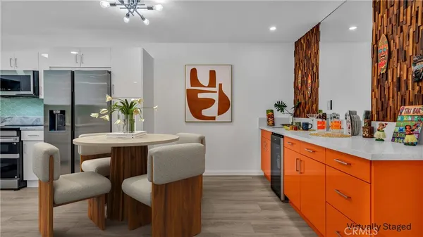 a kitchen with stainless steel appliances granite countertop sink wooden floor dining table chairs and a large window