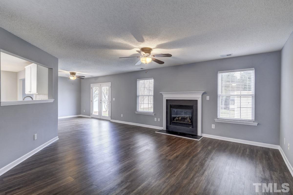 3323 Marcony Way Raleigh, NC 27610 - Photo 2 of 14 an empty room with wooden floor fireplace and windows