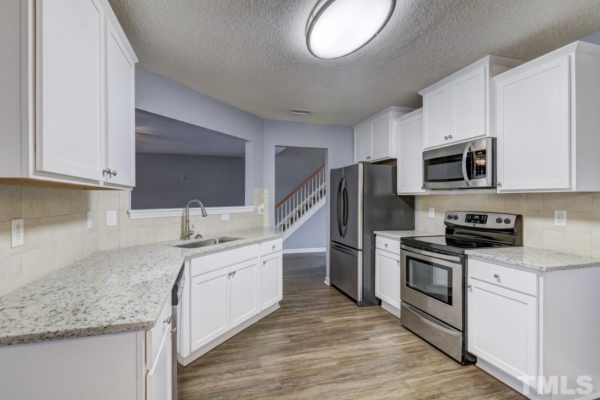 3323 Marcony Way Raleigh, NC 27610 - Photo 5 of 14 a kitchen with stainless steel appliances granite countertop a sink dishwasher stove and microwave with wooden cabinets