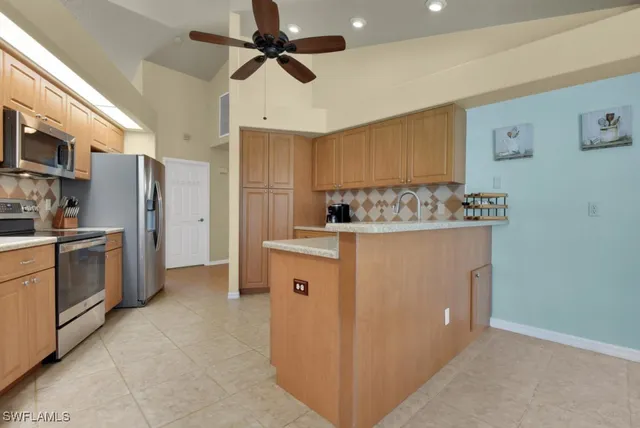 a kitchen with stainless steel appliances kitchen island granite countertop a refrigerator and a stove top oven