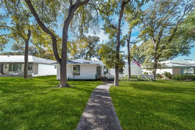 a front view of a house with a garden and trees