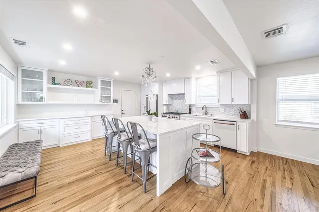 a kitchen with a sink appliances cabinets and a dining table