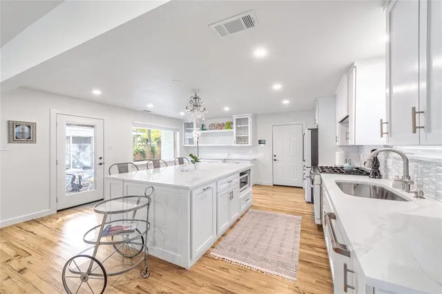 a large white kitchen with lots of counter space a sink and cabinets