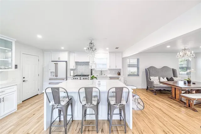 a large kitchen with dining table chairs and wooden floor