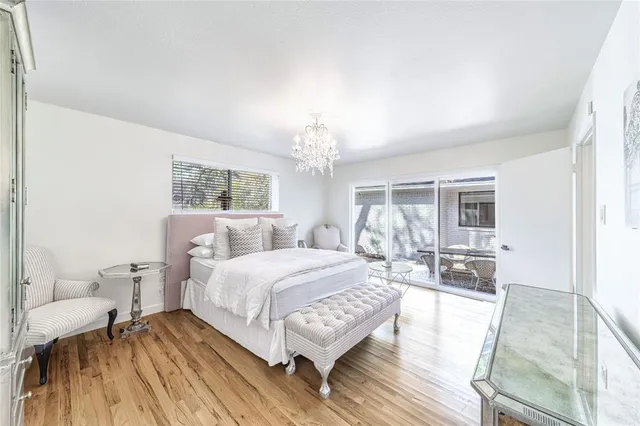 a spacious bedroom with a bed a chandelier and mirror