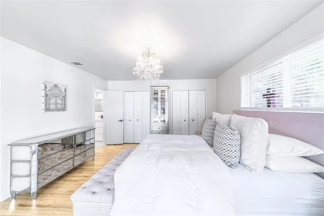 a spacious bedroom with a bed and a chandelier