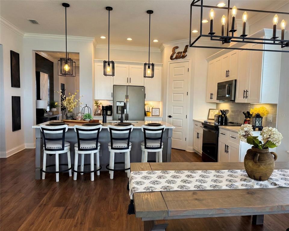 236 Caladium Avenue Lake Alfred, FL 33850 - Photo 15 of 33 a kitchen with stainless steel appliances kitchen island granite countertop a table chairs and a wooden floor