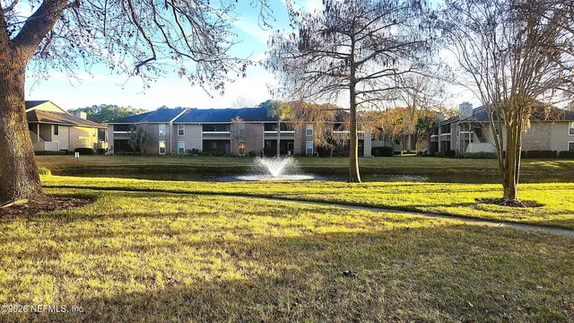 a view of a house with a big yard next to a large tree