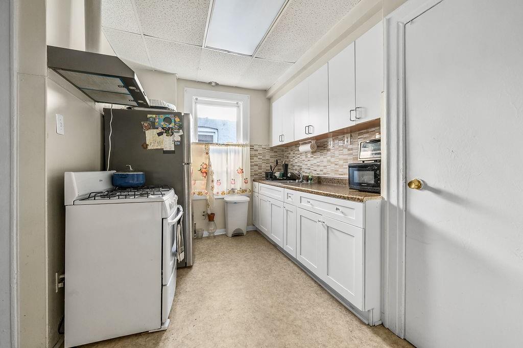 86 Quentin Road Brooklyn, NY 11223 - Photo 16 of 32 a kitchen with sink cabinets and white appliances