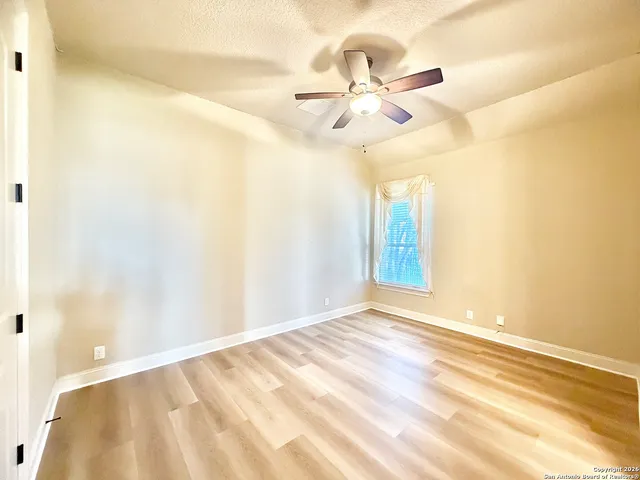 a view of an empty room with chandelier fan and a window