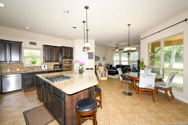 a kitchen with granite countertop a table chairs stainless steel appliances and wooden floor