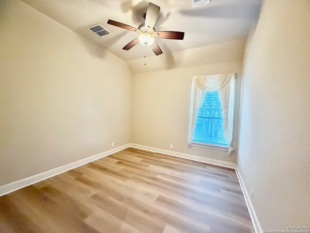 an empty room with windows and fan