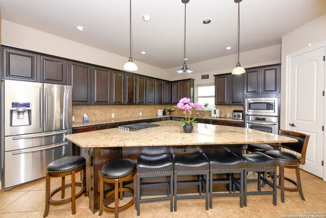 a kitchen with stainless steel appliances granite countertop a stove top oven a sink a dining table and chairs with wooden floor