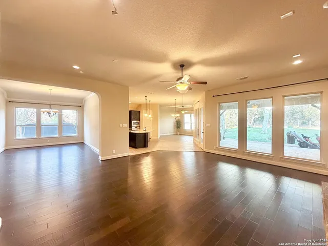 an empty room with wooden floor and large windows