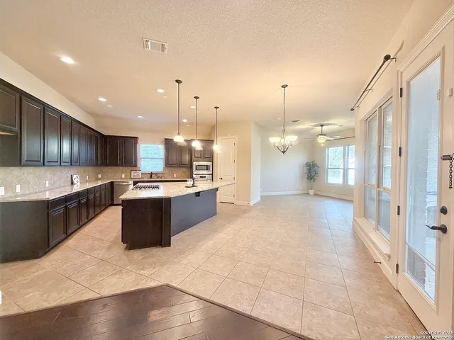 a large kitchen with a large counter top a sink stainless steel appliances and cabinets