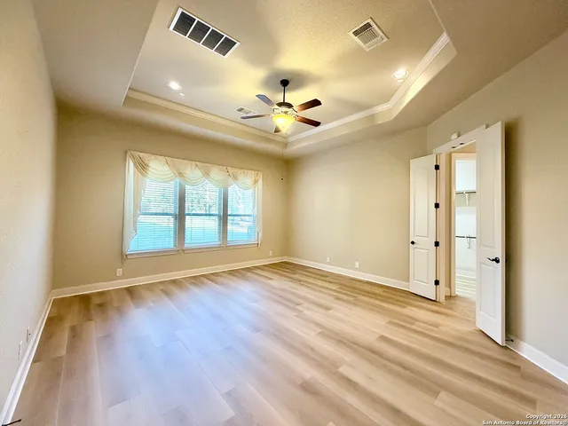 a view of an empty room with a window and wooden floor