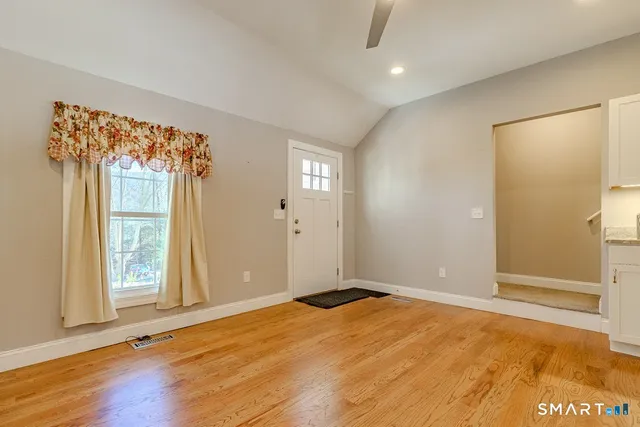 a view of an empty room with wooden floor and a window