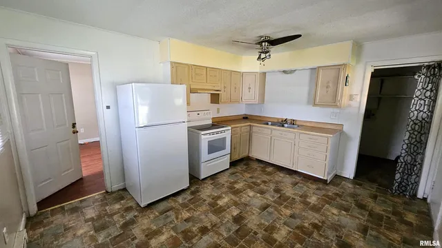 a kitchen with stainless steel appliances a refrigerator a sink a stove a washer dryer and white cabinets